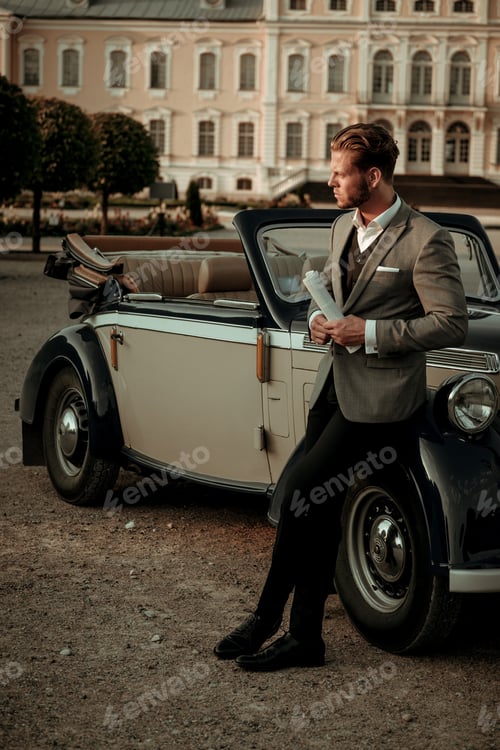 Preview: Confident wealthy young man with newspaper near classic convertible