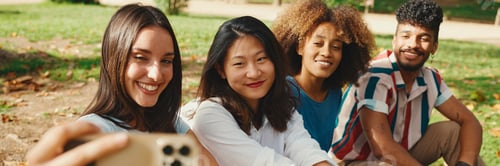 Preview: Happy multiethnic young people are looking at taking selfie on summer day outdoors