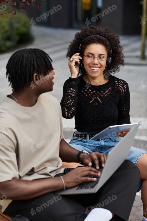 Preview: Young couple enjoying remote work together in vibrant urban setting