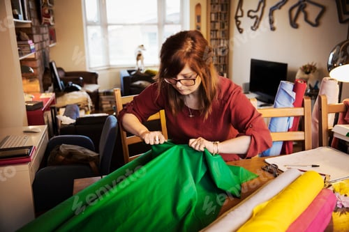 Preview: A woman ripping brightly coloured material on a tabletop in a workroom.