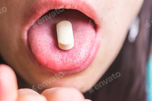 Preview: Closeup shot of a white pill on a person's tongue