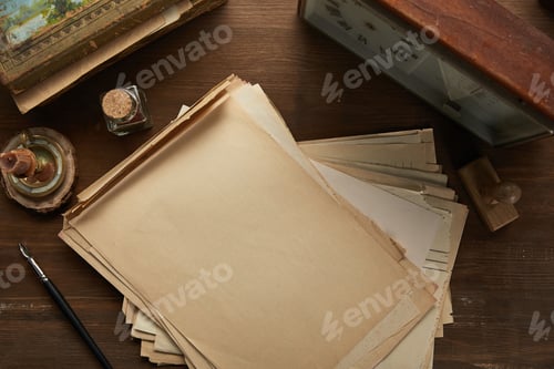 Preview: top view of vintage paper, painting, fountain pen, stamp and clock on wooden table
