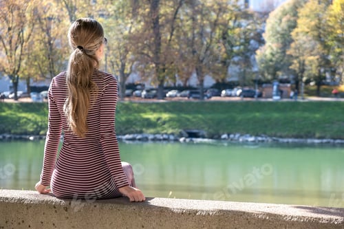 Preview: Young woman in a casual dress and sunglasses resting outdoors on a warm autumn day
