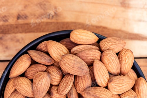 Preview: Close up almonds on black bowl on wooden table background