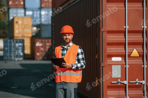 Preview: With tablet in hands. Male worker is on the location with containers