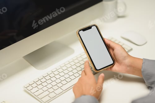 Preview: Closeup female office worker holding smartphone with empty screen sitting at her workplace