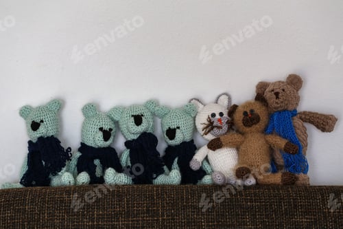 Preview: Line of homemade knitted toys on a sofa