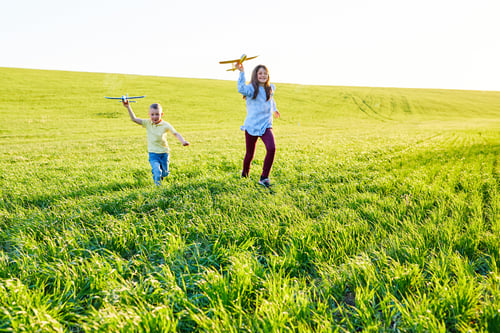 Preview: Happy children play in the field and imagine themselves to be pilots on a sunny summer day
