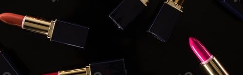 Preview: top view of assorted lipsticks in luxury tubes scattered isolated on black, panoramic shot