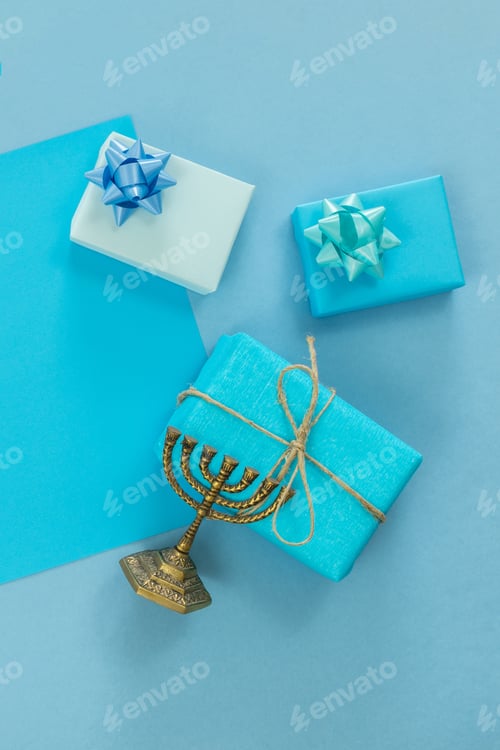 Preview: Vertical top view of bronze traditional candelabra with small gifts against on blue surface