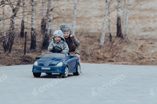 Preview: Two happy kids having fun drive a blue toy car, road trip adventure concept