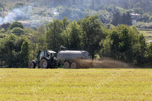 Preview: Farmer spreading organic fertilizer with a tractor in a cultivated field