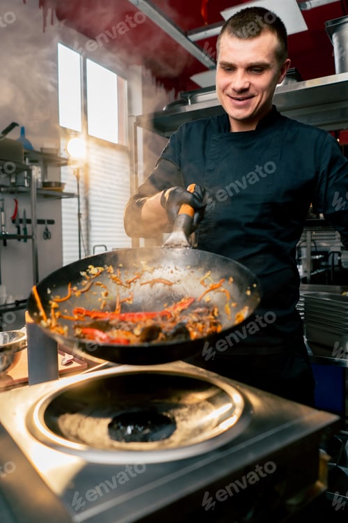 Preview: close-up of a frying pan with egg and meat over the stove with a hand in throw in the air contents
