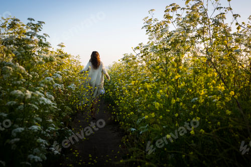 Preview: Woman walking through field of wildflowers