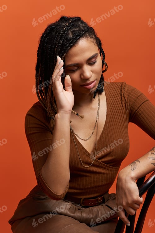 Preview: Young African American woman with braids poses gracefully in a vibrant studio
