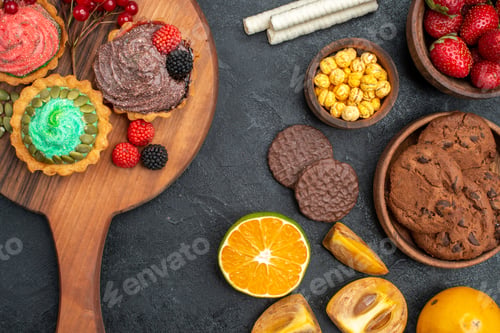 Preview: top view delicious little cakes with biscuits and fruits on a dark background sweet pie cake