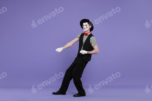 Preview: Funny mime artist in hat posing on purple background