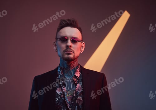 Preview: Fashionable and modern hipster in black suit posing in studio