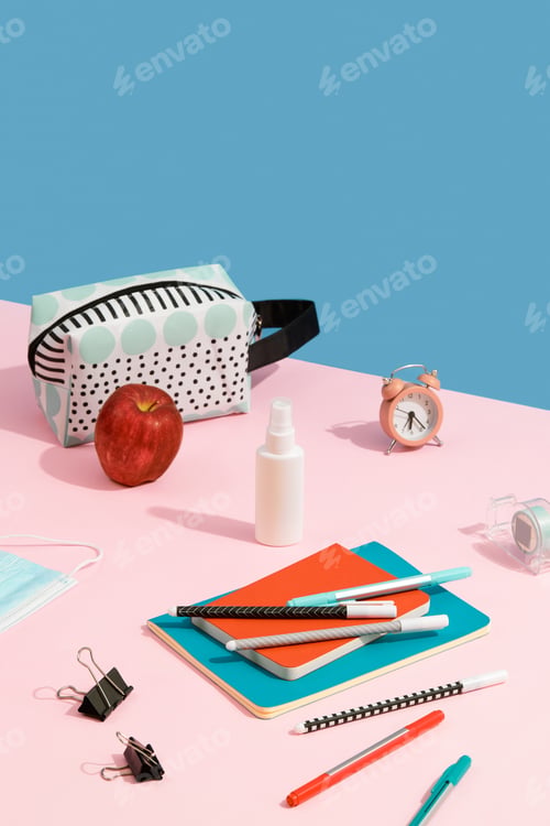 Preview: Alarm Clock, Colorful Notepads, Pens and Hand Sanitizer on Pink Table with Copy Space