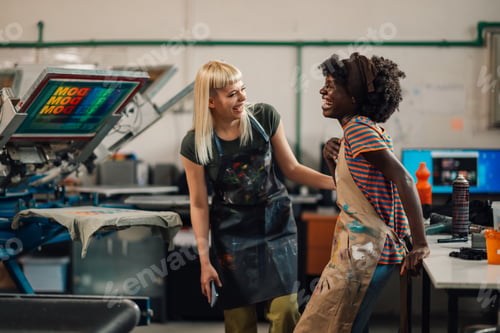 Preview: Cheerful interracial graphic industry colleagues laughing at print shop