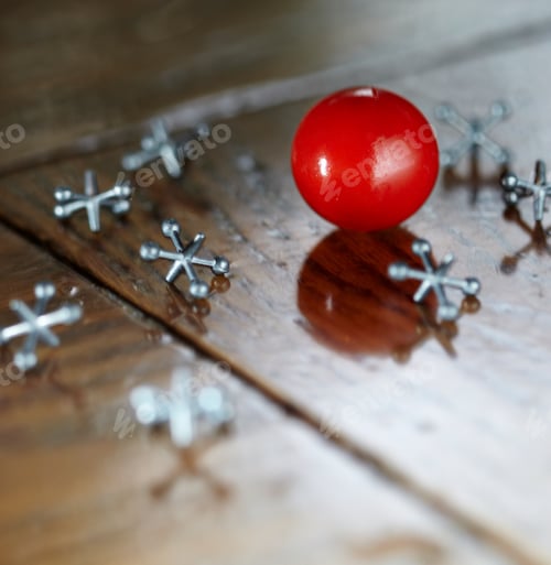 Preview: Ball and jacks counters on a wooden surface.