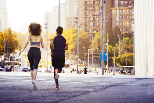 Preview: rear view of a couple running at sunset at city