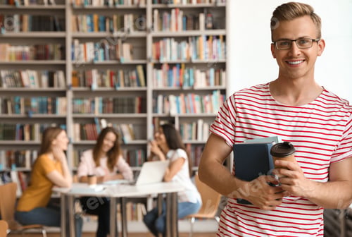 Preview: Young man with books and drink in library. Space for text