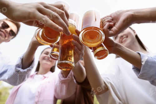 Preview: Group of happy friends clinking glasses of beer outdoors, bottom view