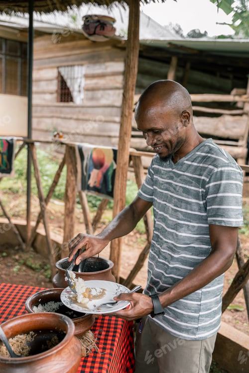 Preview: African man preparing traditional Tanzanian dish on a rural kitchen