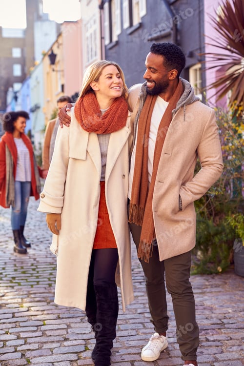 Preview: Multi Cultural Couple With Friends Walking Along Residential City Street In Fall Or Winter