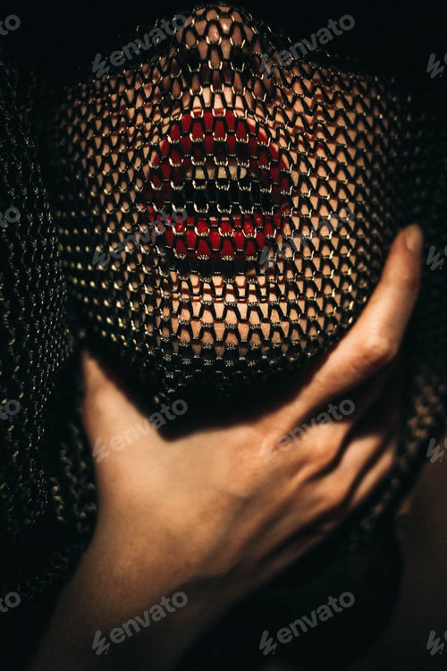 Preview: Woman in red lipstick with a fishnet over her face, hand around her neck in a chokehold.