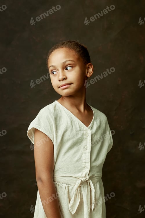Preview: Studio Portrait of Black Girl in White Dress Looking away on Brown Background