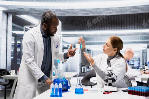 Preview: Team of biochemists in lab inspecting blue liquid clarity in test tube