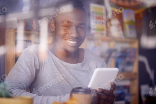 Preview: Cropped shot of a handsome young man using his tablet while sitting in a cafe