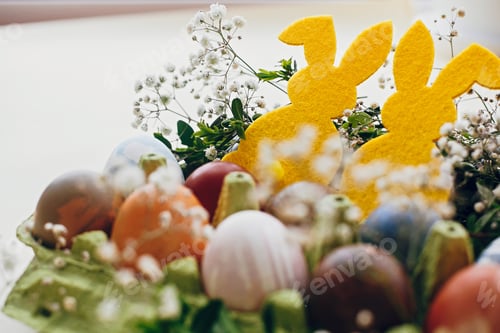 Preview: Stylish easter eggs, yellow bunny in nest of spring flowers