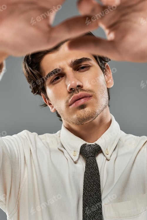 Preview: Stylishly dressed young man poses confidently in a modern studio setting on a grey backdrop