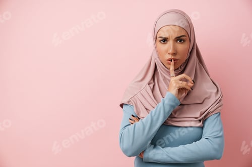 Preview: An upset muslim woman wearing pink hijab showing a silence gesture