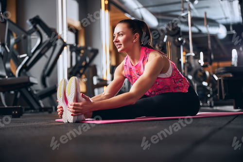 Preview: Cheerful female stretching legs in sport club