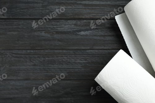 Preview: Rolls of paper towels on black wooden table, top view. Space for text