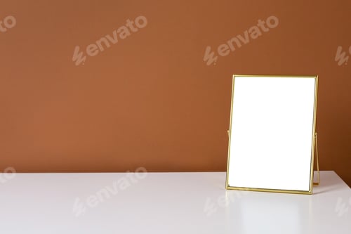 Preview: Gold frame copyspace on white table with dark orange wall background