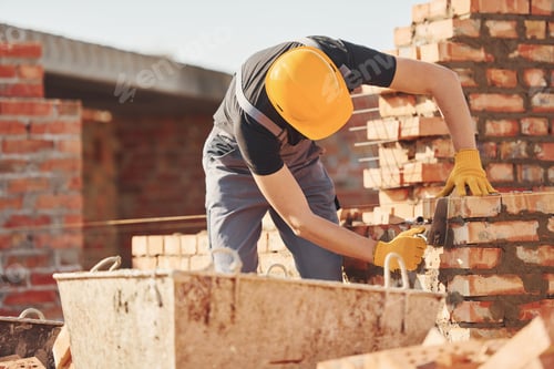 Preview: Busy with brick wall. Construction worker in uniform and safety equipment have job on building
