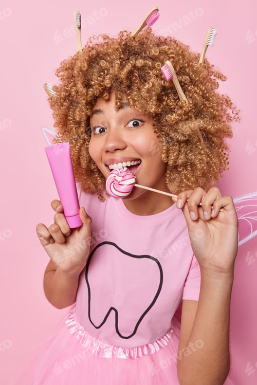Preview: Curly haired European woman embodies essence of tooth fairy holds toothpaste and wand shaped like