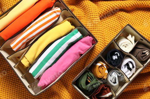Preview: Organizers with folded clothes on orange blanket, flat lay