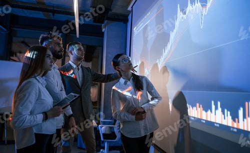 Preview: Standing together. Male leader talking to employees, showing the plan on the projector in office