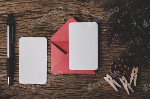 Preview: Two blank card with red envelope and pen is placed on wood.