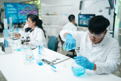 Preview: Research team analyzing experiment results with glassware and chemicals in a modern medical