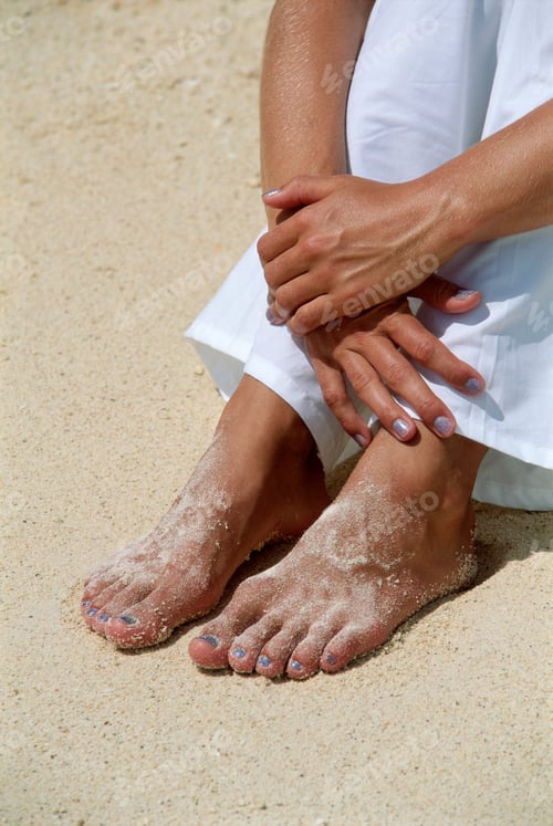 Preview: Young woman's feet covered in sand