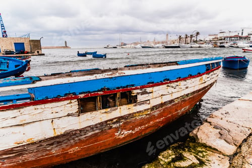 Preview: Bari, Italy - March 12, 2019: Blue wooden boat washed by time and waves in a harbor.
