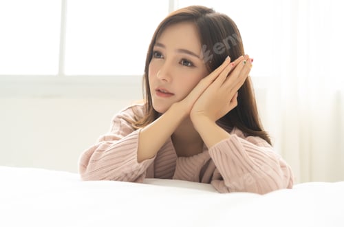 Preview: Portrait of a beautiful young Asian woman smiling, with hands on her face.