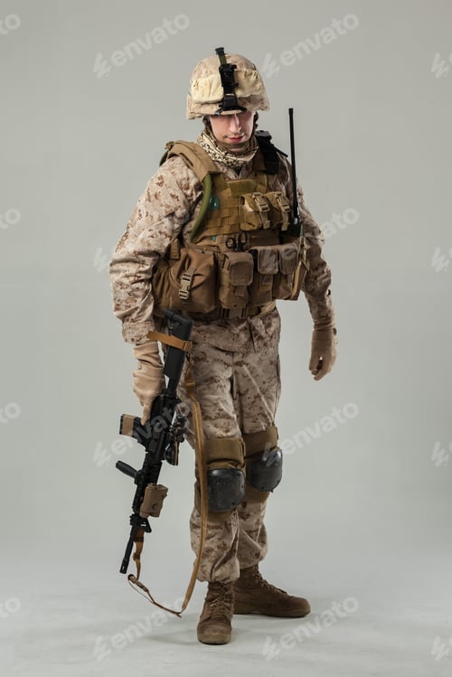 Preview: Military soldier in camouflage uniform poses with weapon in studio setting